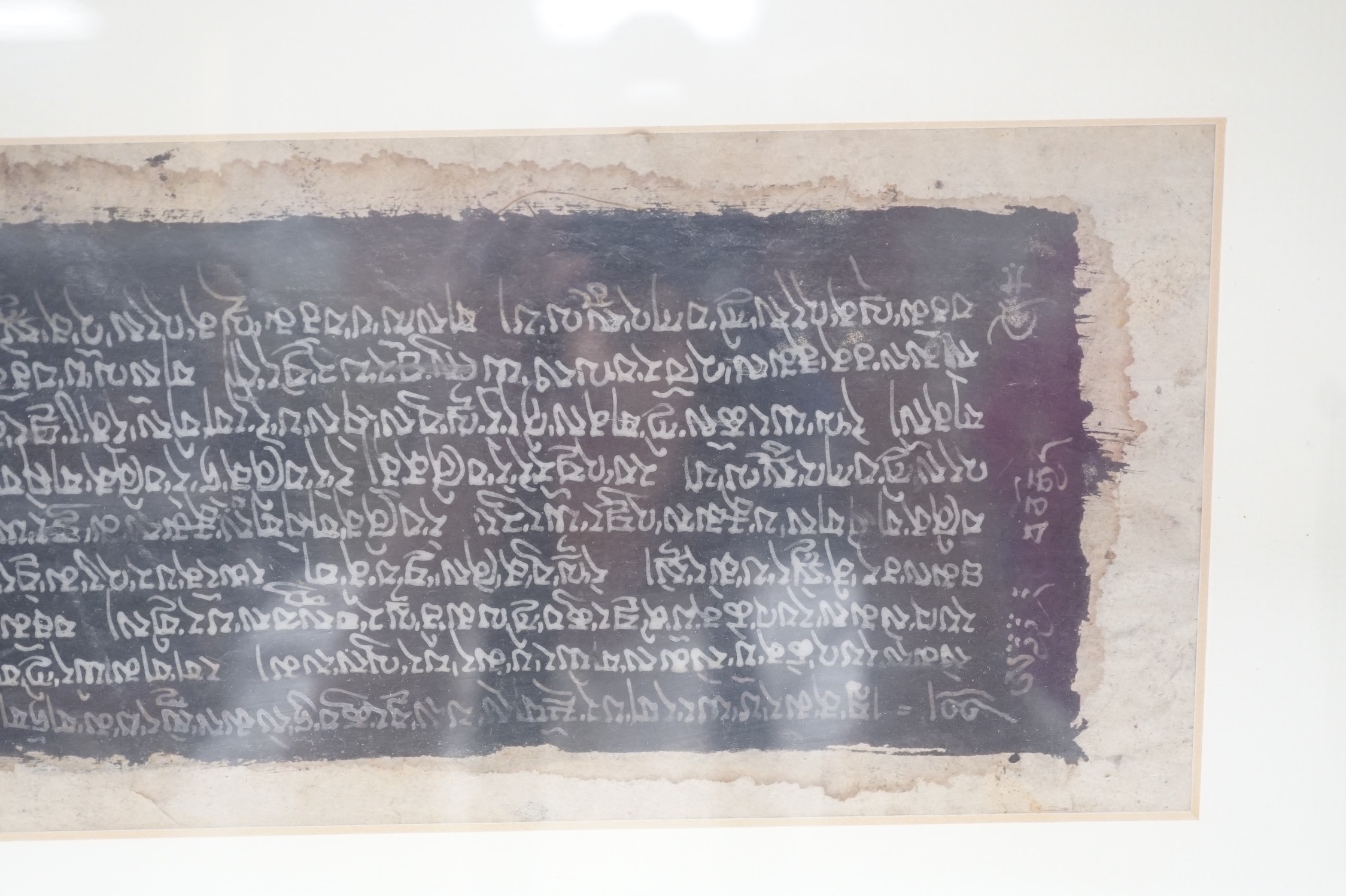 A framed Tibetan Sanskrit sutra panel, 45cms x 13cms.